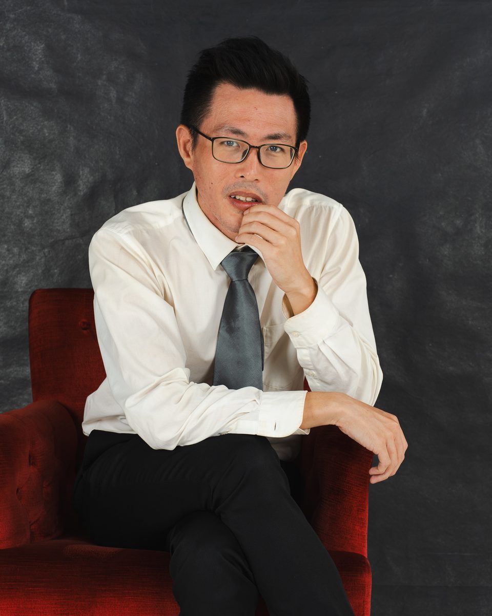 Tony in a red armchair, hand at his chin