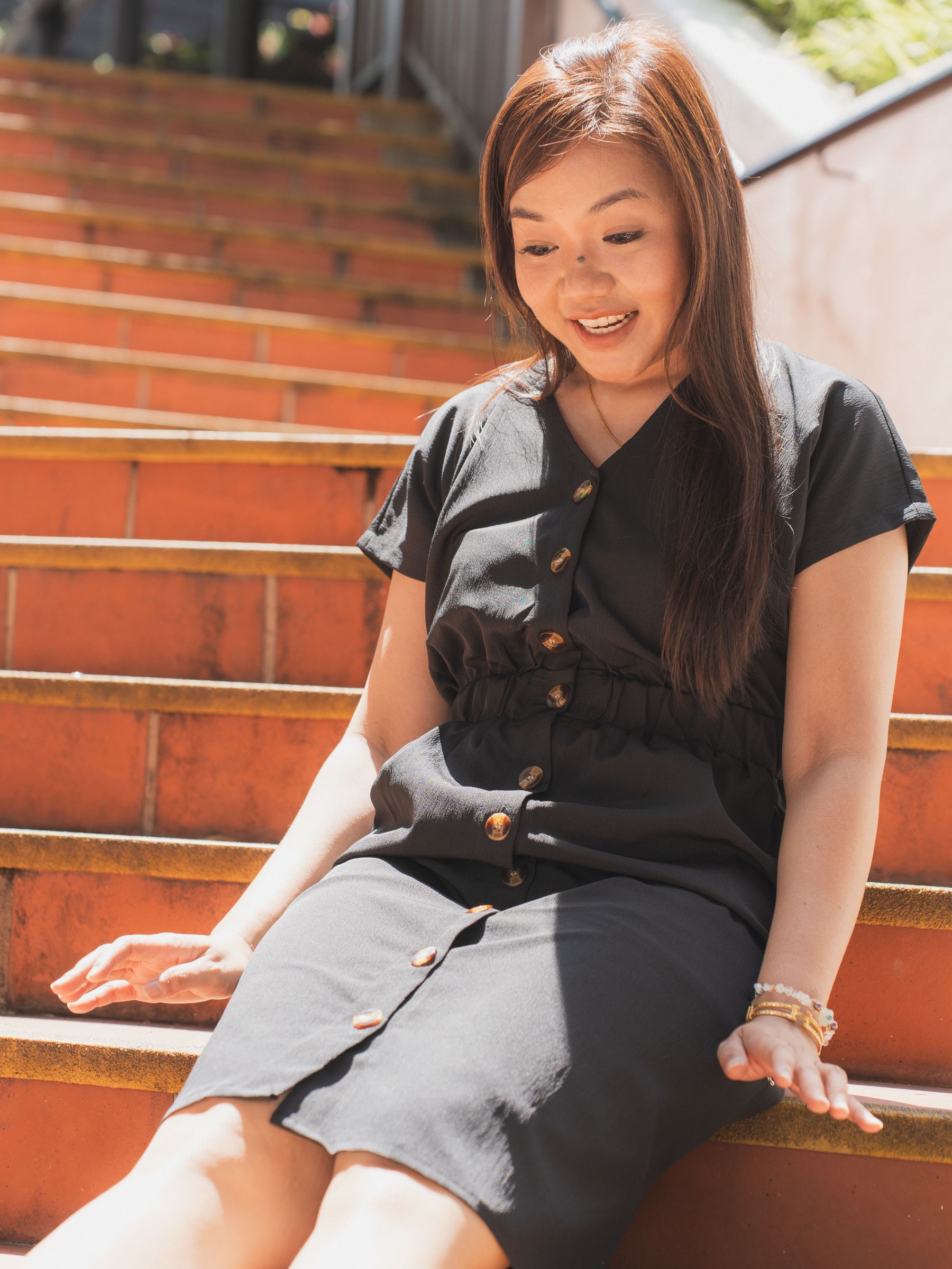 Solo portrait, warm candid smile on red steps