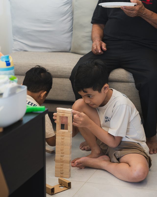 Two boys playing a block-stacking game on the floor