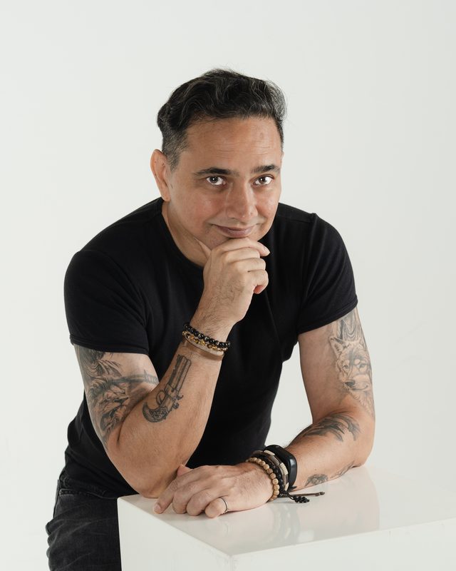 Renay leaning on a table, hand at his chin