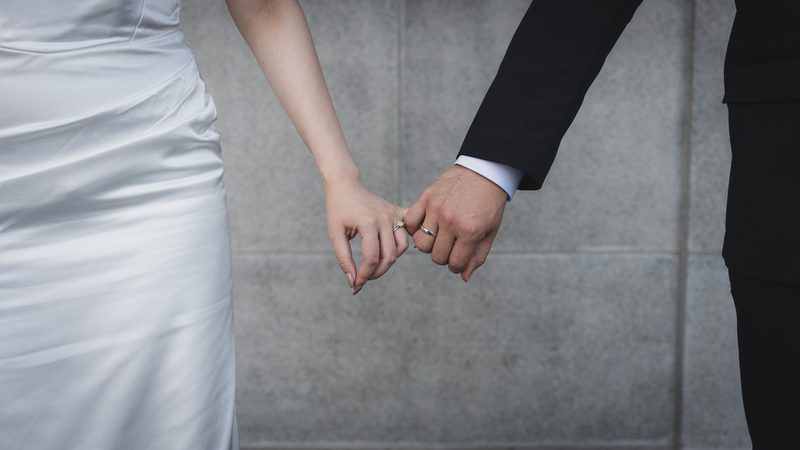 Holding hands, the gown beside the suit