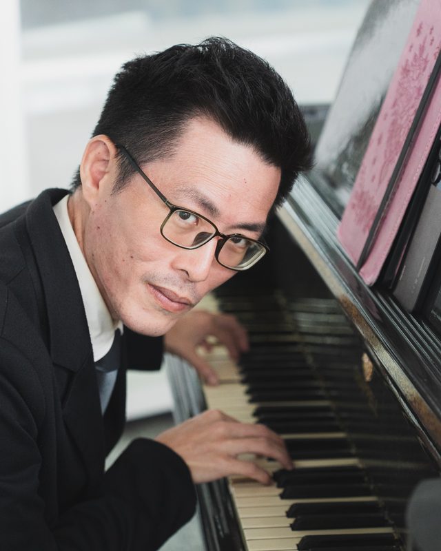 Tony leaning over the piano keys, smiling