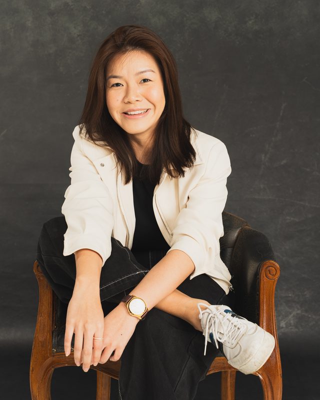 Wylie smiling in a leather armchair on a dark backdrop