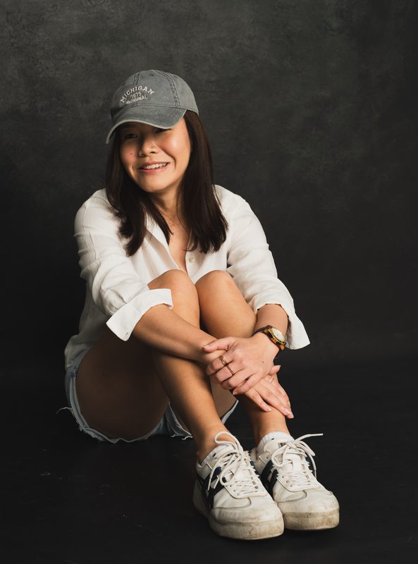 Wylie in a cap hugging her knees